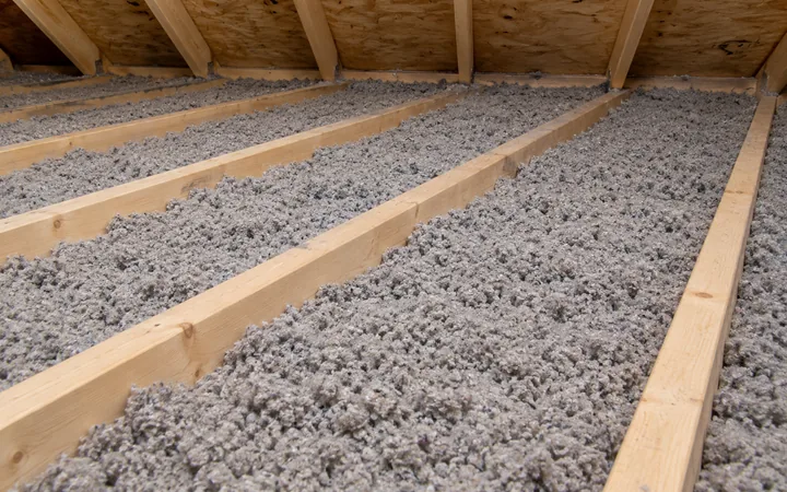 Solives de plafond parallèles entourées d’isolant de cellulose dans un entretoit